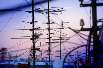 Television antennas and electric wires against the background of the evening sunset sky