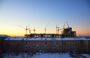 A tall multi-storey house stands in the rays of the setting sun against the sky
