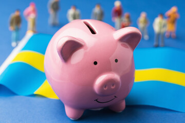Ceramic piggy bank, Swedish flag and plastic toy men on a blue background, concept on the theme of...