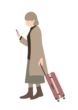 スーツケースを手に、携帯電話の画面を見るシニア女性（旅行等のイメージに）