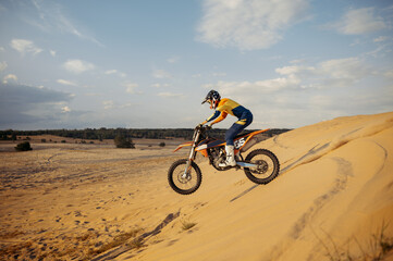 Fototapeta na wymiar Professional motocross rider sliding down sand hill