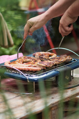 Man preparing food on electric barbecue in the garden 