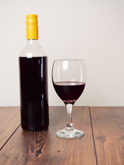 Still life scene. Bottle of red wine and one glass and wooden bowl with dark grapes. Bright color background. Food industry product.