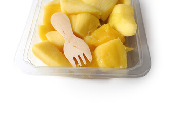 Fresh mango chunks and a small wooden ecology friendly fork in a plastic tray on white isolated background. Food supply industry. Exotic fruit product. Healthy food. Fruit snack for lunch.