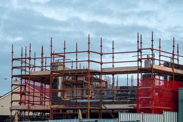 Small house renovation. Scaffolding around the walls. Construction industry. Cloudy sky background....