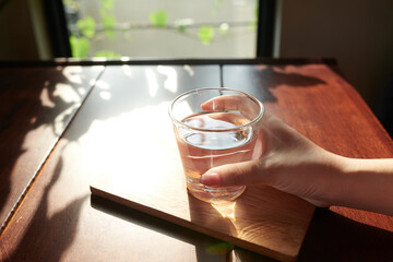 Close-up image of woman drinking glass of fresh water before starting working day