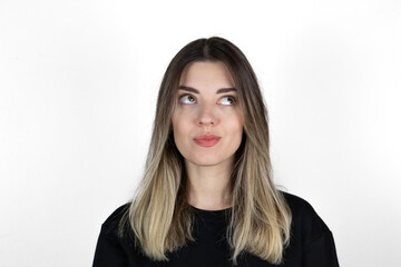 Obraz premium Close up portrait of young cheerful beautiful girl with blonde hair in casual clothes posing for college photo, smiling, looking up with happy and thoughtful facial expression.