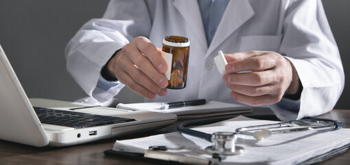 Caucasian doctor holding bottle of pills.