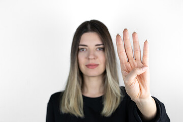 Young blonde girl wearing casual clothes standing over isolated white background showing and pointing up with fingers number four while smiling confident and happy. Focus is on her hand.