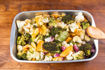 Baked broccoli, cauliflower, peppers and onions in a metal baking sheet - a simple vegetarian delicious dish, top view