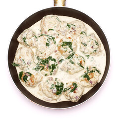 Delicious small meatballs with spinach in a creamy sauce in the frying pan
