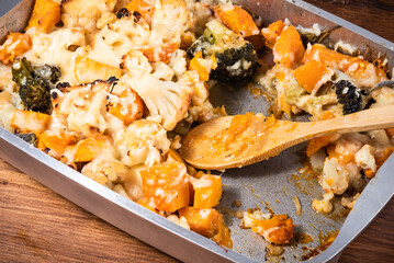Baked vegetables broccoli, cauliflower, pumpkin, peppers and onions with cheese in a metal baking sheet - simple healthy vegetable dish