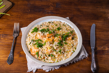 Shrimp risotto - portion in a plate on the table with a fork and knife