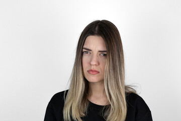 Obraz premium Young girl with serious and angry expression on her face. She is in anger. She asked something and she is waiting answer. White studio background.