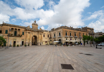 Fototapeta na wymiar Lecce, Puglia, Italy. August 2021. Amazing view walking towards one of the access gates to the historic center. People come out of the old town through it. Beautiful summer day.