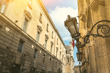 Fototapeta na wymiar Lecce, Puglia, Italy. August 2021. View of one of the streets of the historic center with a characteristic vintage lantern lamp post. Beautiful summer day.