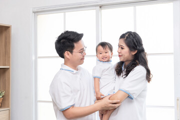 Fototapeta premium Asian happy family, father and mother kissing their baby at home.