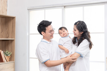 Fototapeta premium Asian happy family, father and mother kissing their baby at home.