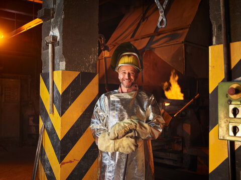 Smiling metal worker wearing protective workwear in steel mill