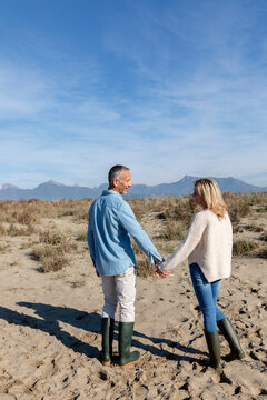 Man and woman holding hands standing at dunes