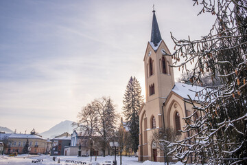 Fototapeta na wymiar Dolny Kubin, Slovakia - December 26 2021: City centre of Dolny Kubin during Christmas time. Hviezdoslavov Square with towers of local churches. Snowy landscape and historic houses. Orava region