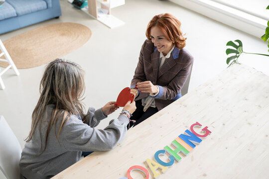 Smiling woman gifting heart shape to coach