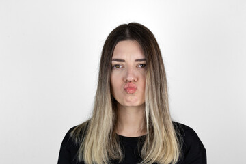 Fototapeta premium The girl in casual clothes, pursed lips. White studio background.