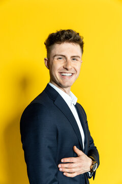 Smiling young businessman at yellow background