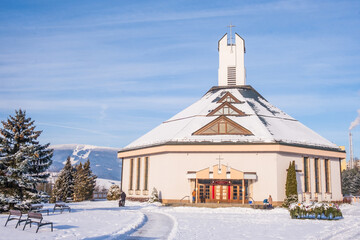 Dolny Kubin, Slovakia - December 26 2021: New Catholic Church Povysenia Svateho Kriza with view of Ski Park Kubinska Hola in the background. Christmas season, winter time in Orava region. © Zuzana