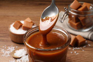 Taking tasty salted caramel with spoon from glass, closeup