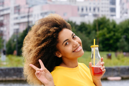 Smiling woman with lemonade bottle in park