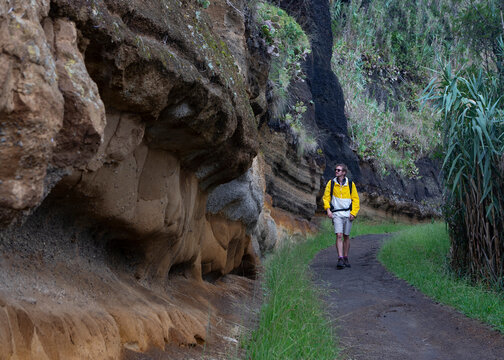 Hiker with backpack walking on road by rock formation