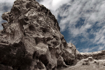 Gray rock in Charyn canyon against the blue sky, clear summer day, clouds in the sky, summer in the canyon, the rock goes into the horizon