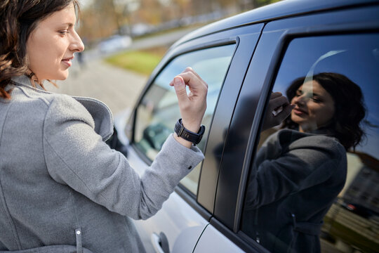 Woman in jacket unlocking wristwatch with car door
