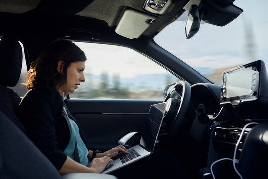 Businesswoman using laptop in driverless car