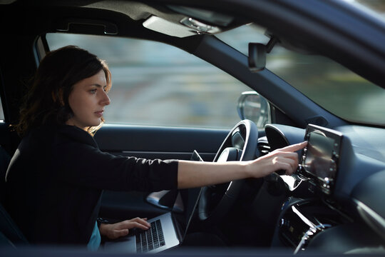Businesswoman with laptop using navigation device in driverless car