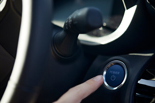 Businesswoman pointing at electric car start button