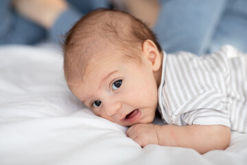 Closeup Portrait Of Cute Funny Newborn Baby Lying In Bed