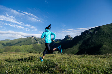 Young woman ultramarathon runner running at mountain top