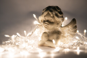 statuette of an angel on a white background with garlands