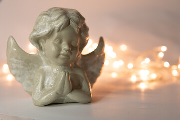 statuette of an angel on a white background with garlands