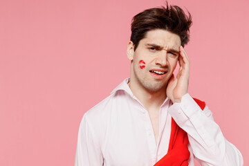 Obraz premium Young confused sad caucasian man 20s with lipstick lips on face wearing casual shirt sweater have headache isolated on pink background studio. Valentine's Day birthday holiday party dating concept