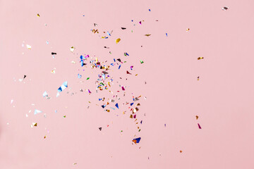 Multi-colored sequins on a pink background. Festive background with confetti.