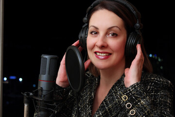 Female Vocalist In Recording Studio;  Close up female vocalist in recording studio singing into microphone