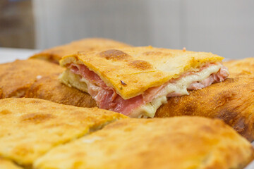 Focaccia croccante ripiena di prosciutto cotto e mozzarella fotografata in una vetrina di una rosticceria