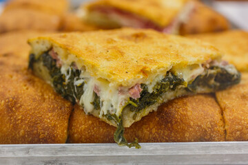 Focaccia croccante ripiena di salsiccia, friarielli e mozzarella fotografata in una vetrina di una rosticceria