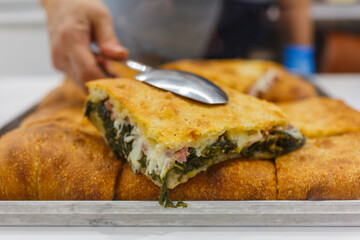 Focaccia croccante ripiena di salsiccia, friarielli e mozzarella fotografata in una vetrina di una rosticceria