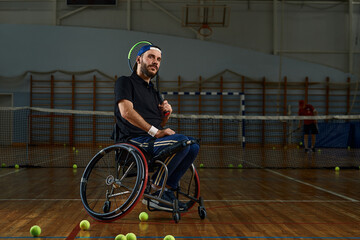 Fototapeta na wymiar Young man in wheelchair playing tennis on court