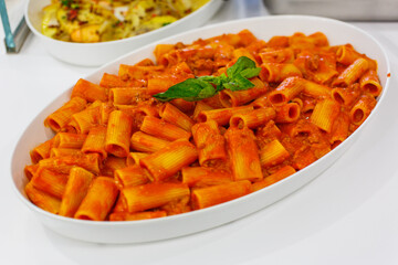 Pirofila di ceramica con pasta al sugo di pomodoro guarnita con basilico