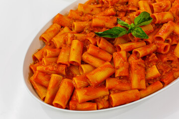 Pirofila di ceramica con pasta al sugo di pomodoro guarnita con basilico